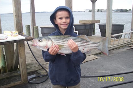 A kid wearing a blue hoodie while holding a fish