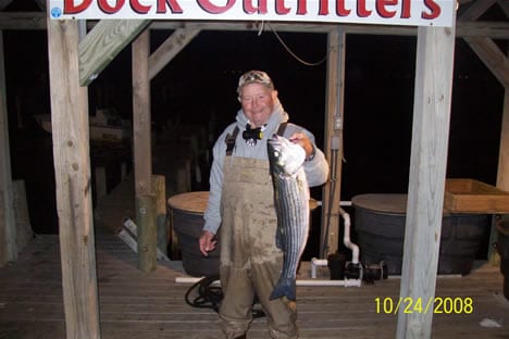 A man wearing a gray jacket while holding a big fish