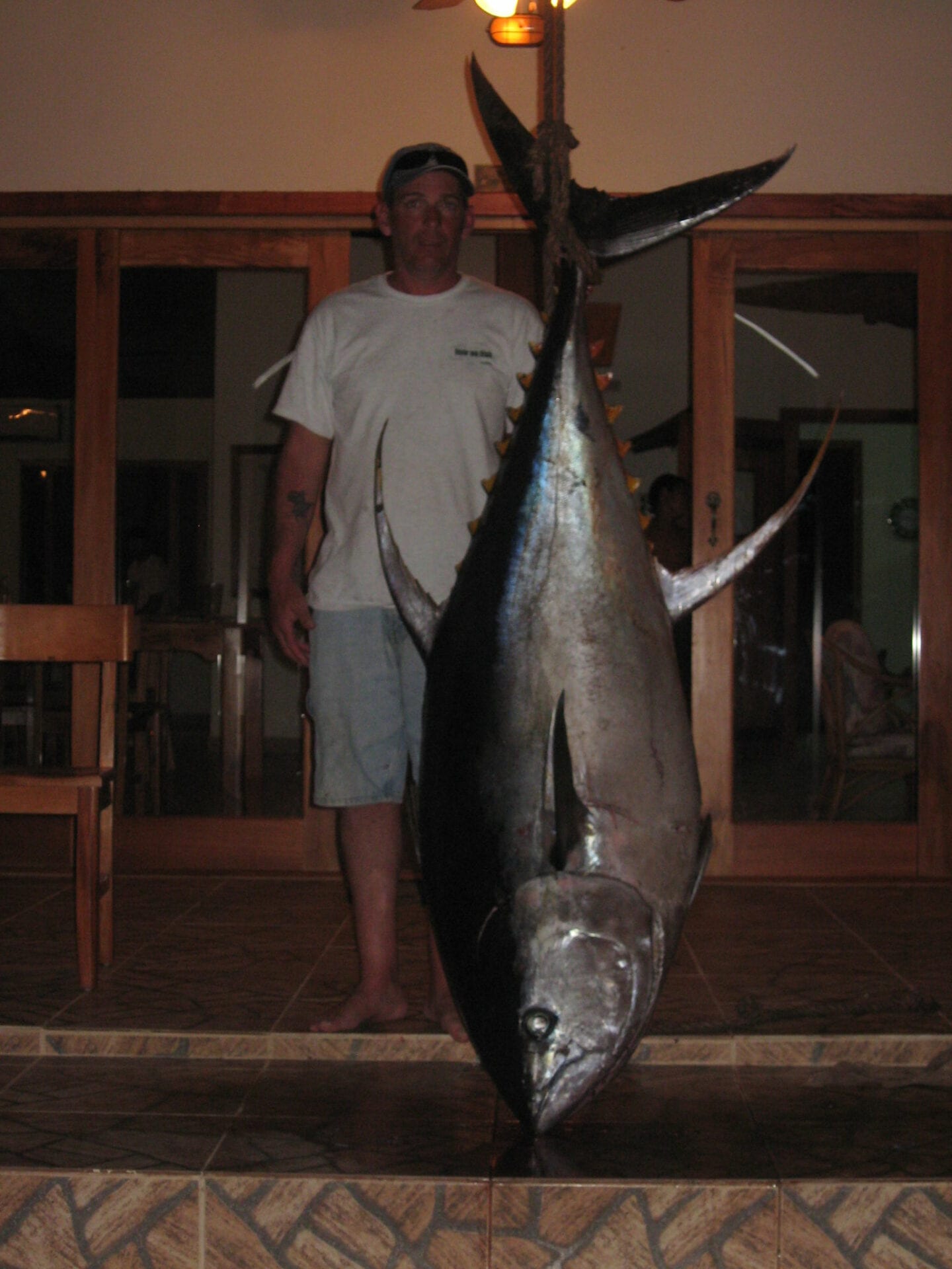 A man in the front door while holding a big fish