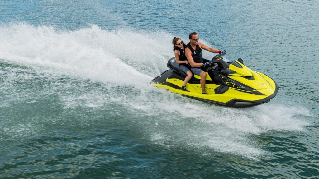 Two people riding a yellow jet ski on choppy water.