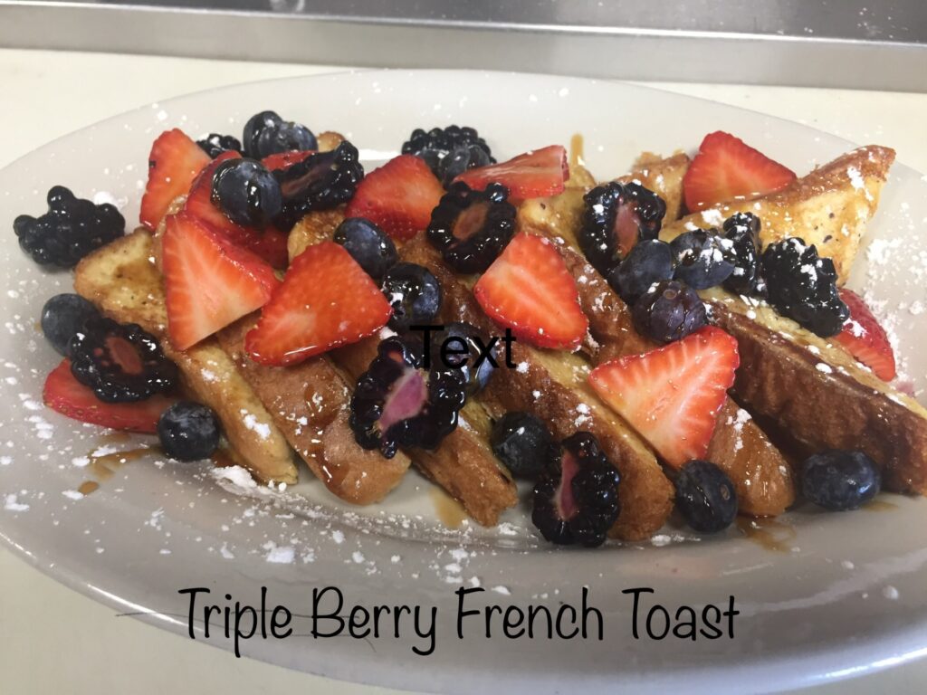 Triple Berry French Toast with strawberries, blueberries, and syrup.