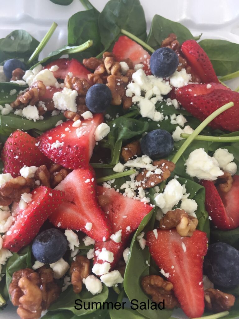 Fresh salad with strawberries, blueberries, nuts, and feta cheese.