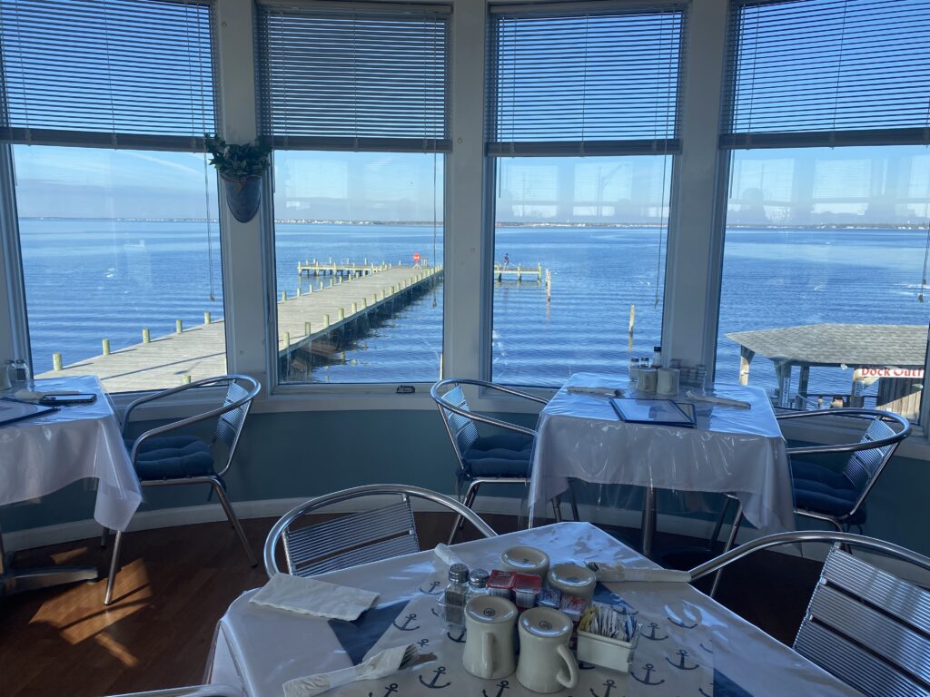 Dining area with large windows overlooking a pier and ocean.